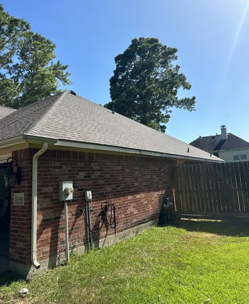 Side elevation of a brick home after roof replacement in Cypress TX