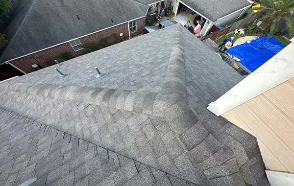 Rear hips of a new Weathered Wood roof in Cypress with the chimney