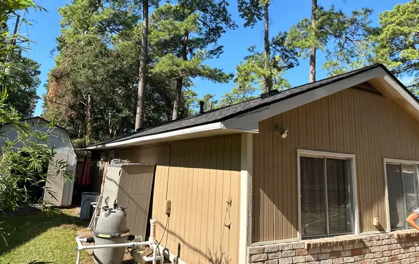 Side elevation of a Cypress home under pines with the new charcoal roof