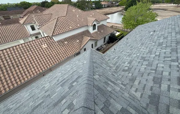 New charcoal shingle roof beside tile-roofed neighbors in a lakefront Houston neighborhood
