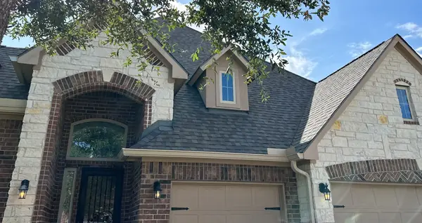 Front gable and entry of a stone-and-brick Cypress home with the new roof