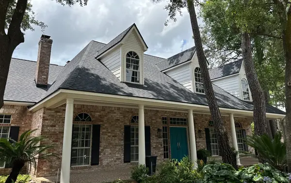 Front dormers and porch of a two-story Cypress home with a new dark gray roof