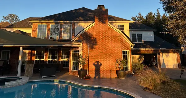 Brick chimney re-flashed on a new Houston roof over the pool