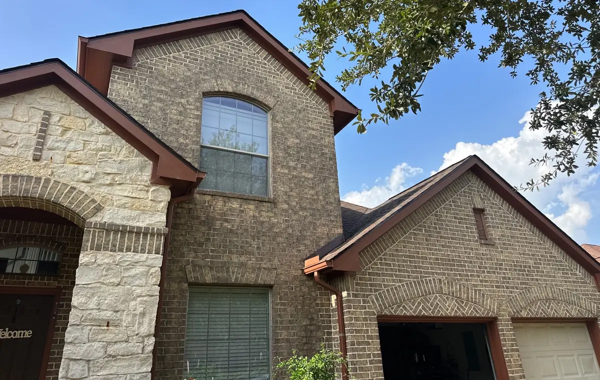 Front gable of a stone-and-brick Cypress home with a new dark brown roof