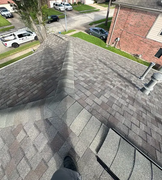Hip and ridge caps of a new gray-brown roof in Cypress looking toward the street