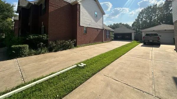 Driveway view of a Houston home with a new roof and gutters