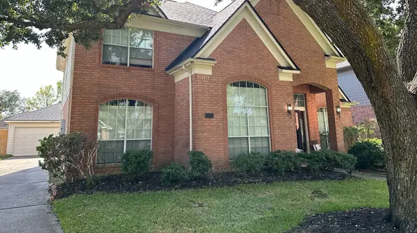 Street view of a replaced roof under live oaks in northwest Houston