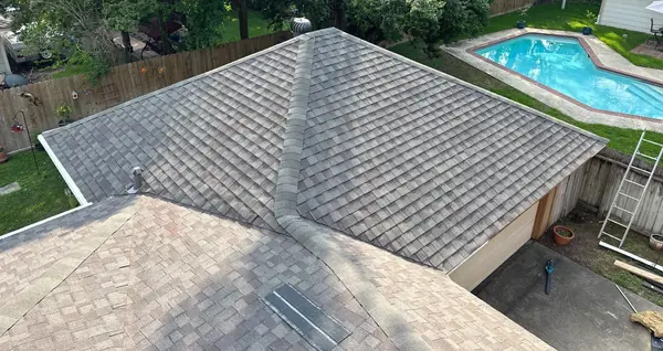 Ridge and hip caps of a new gray roof in Cypress with the ladder still set