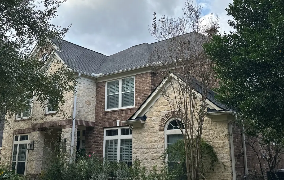 Front of a two-story brick-and-stone Katy home with a new charcoal roof