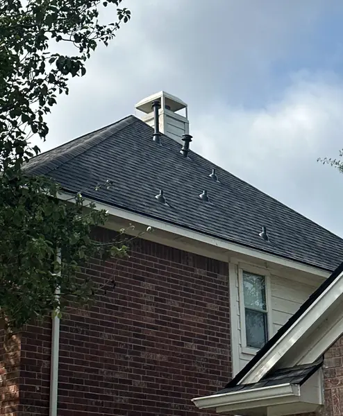 New charcoal shingles and ridge of a two-story Cypress home
