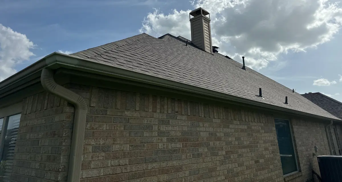 Side elevation of a brick Cypress home with the new gray-brown roof and chimney